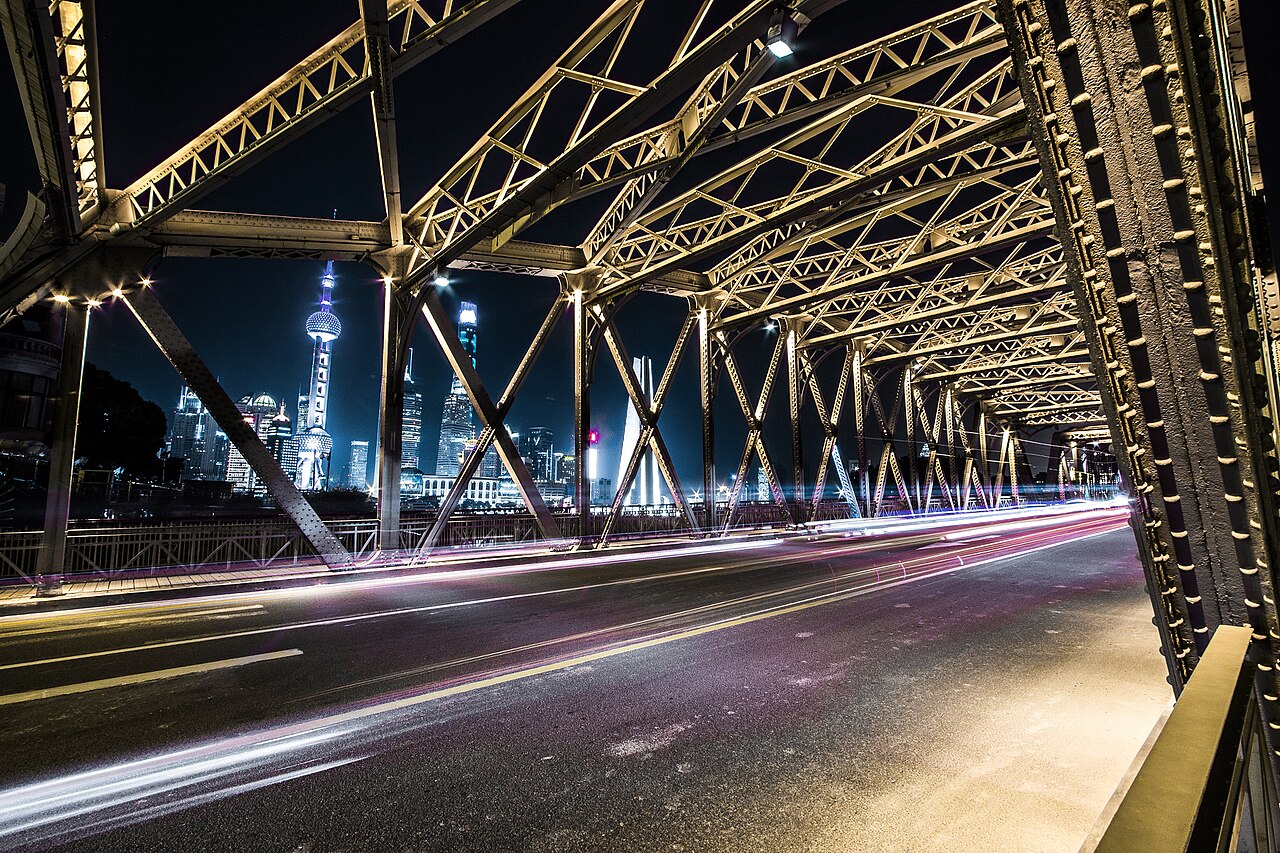 Shanghai Bund night view through Waibaidu Bridge steel frame with Pudong skyline