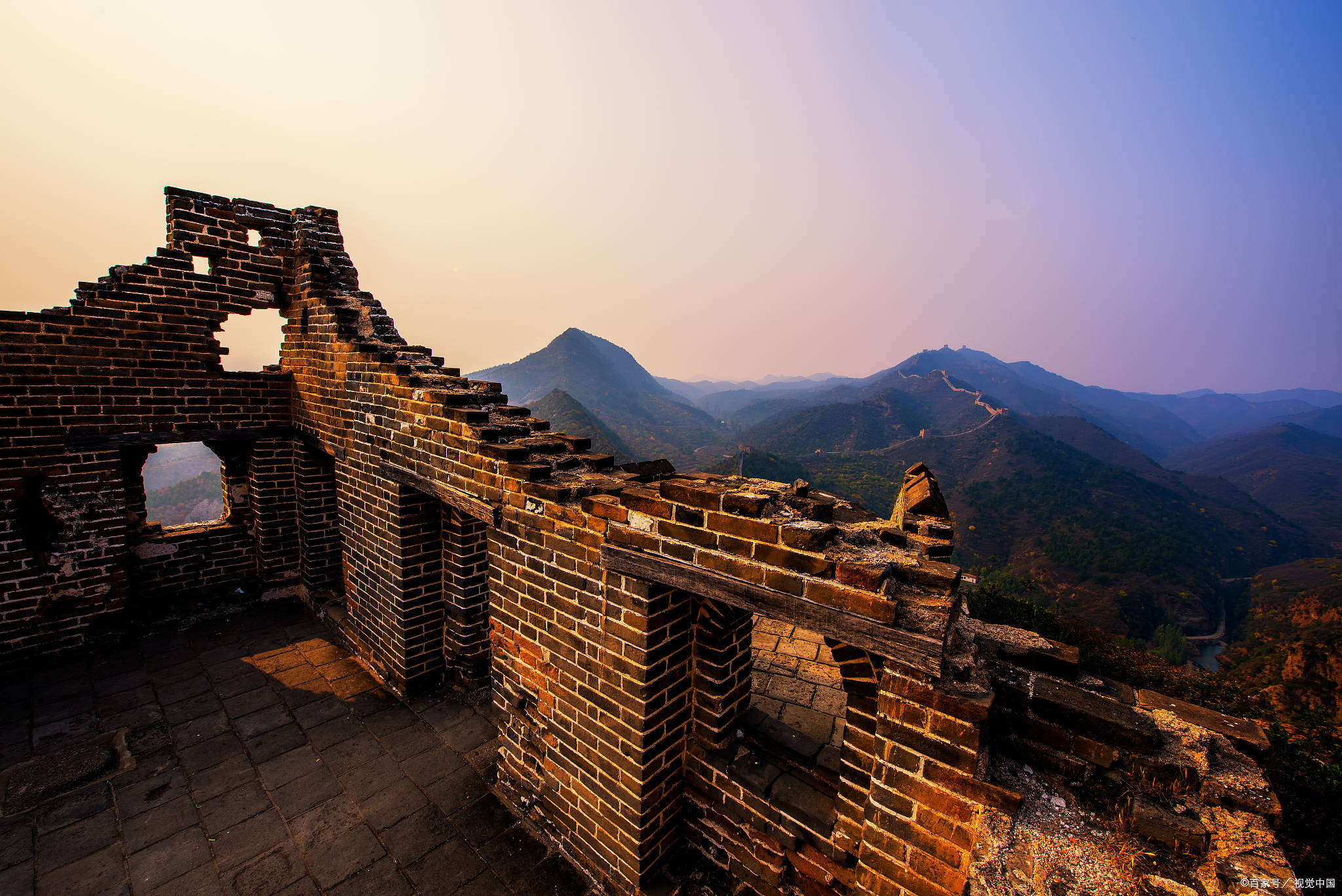 Ancient Great Wall watchtower ruins with weathered bricks overlooking mountain valleys