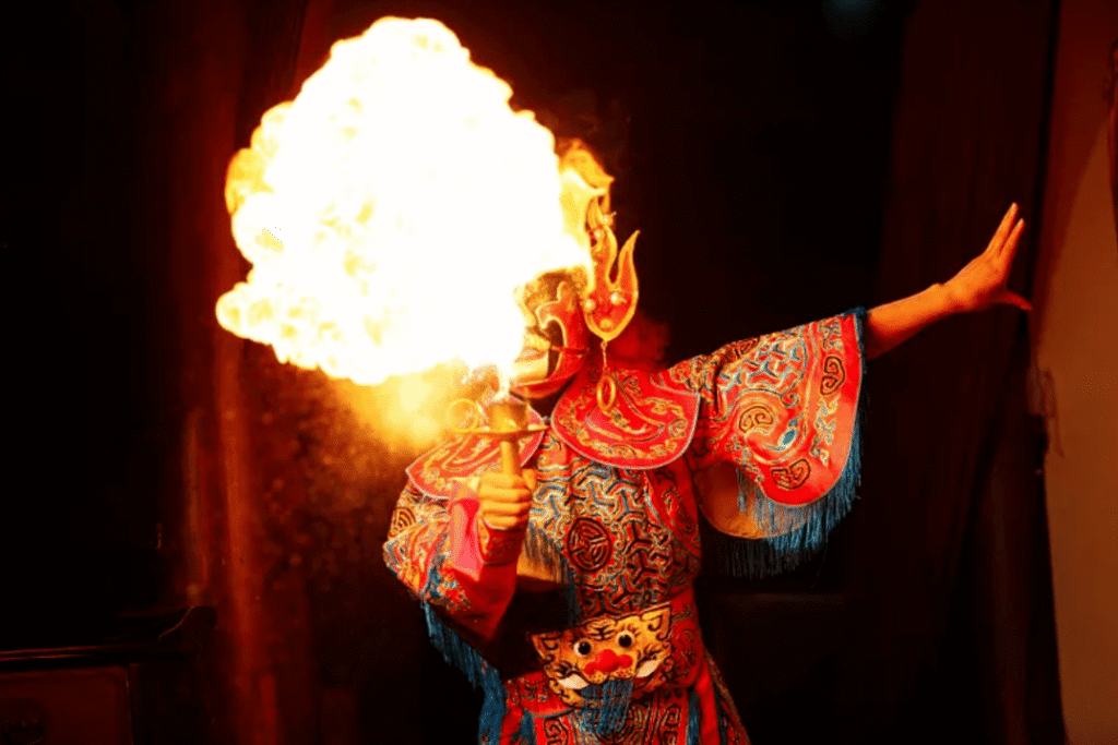 Sichuan opera performer in colorful costume performing fire breathing on stage