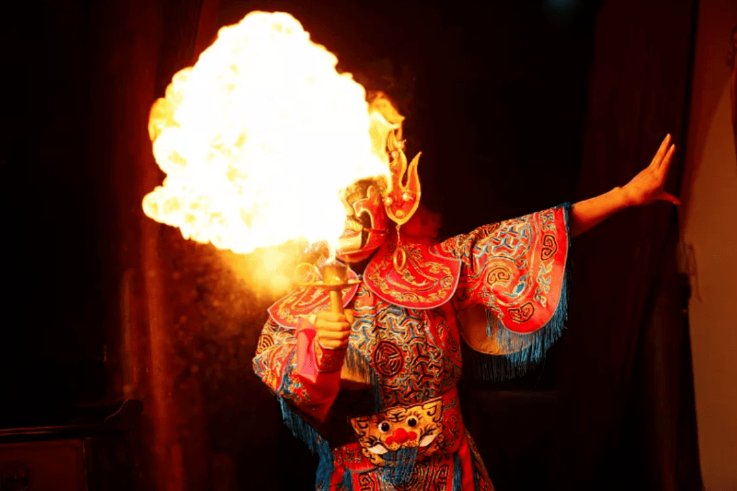Sichuan opera performer in colorful costume performing fire breathing on stage
