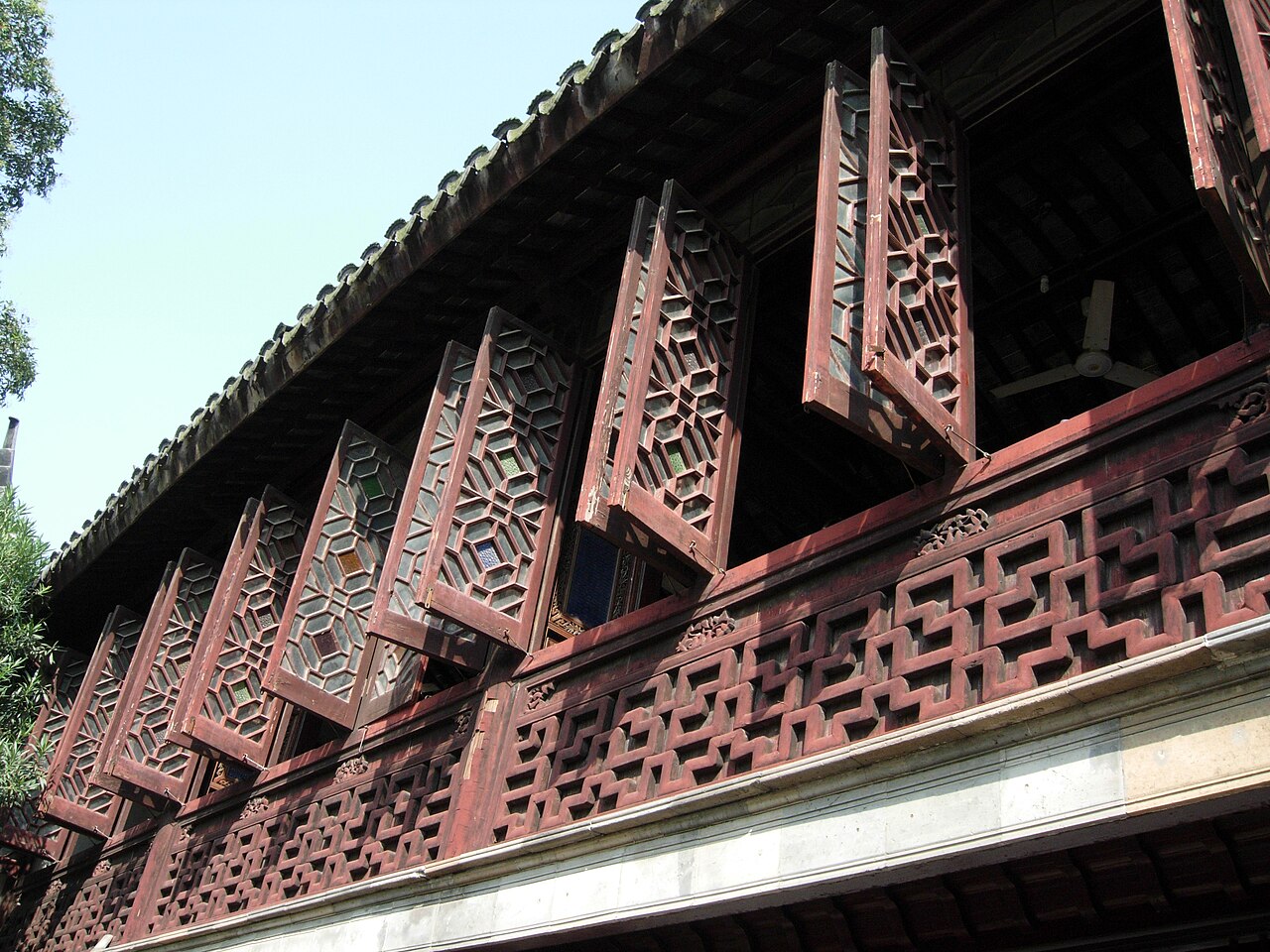 Classical Suzhou garden courtyard — white-washed walls, dark-tiled roof, and manicured greenery in traditional style